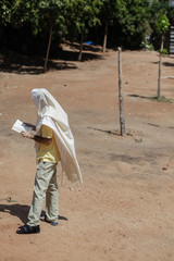 Jewish man wrapped with Talit praying outdoors. 