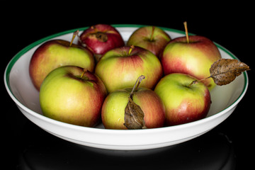 Lot of whole fresh garden apple in white bowl isolated on black glass