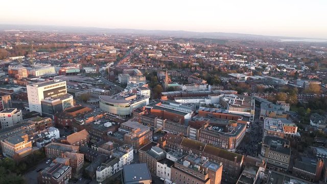 Busy Exeter city centre. Aerial over the town at sunset or golden hour. Princesshay, shopping centre, the cathedral and the east side of the city are visible.