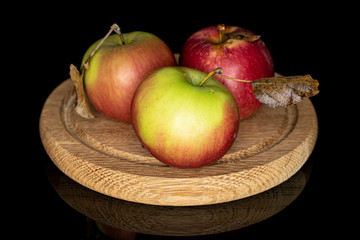 Group of three whole fresh garden apple on wooden plate isolated on black glass