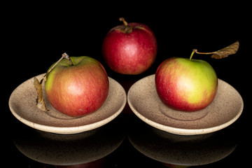 Group of three whole fresh garden apple on two plates isolated on black glass