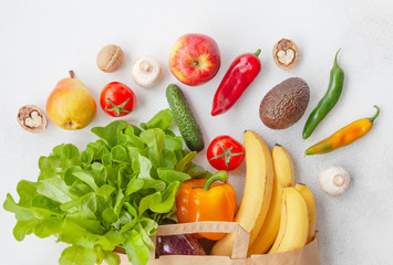 Paper bag of different health food. Vegetables and fruits in a supermarket paper bag top view.