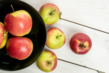 Lot of whole fresh garden apple in dark bowl on white wood