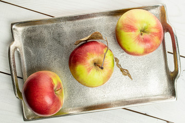 Group of three whole fresh garden apple on tray on white wood