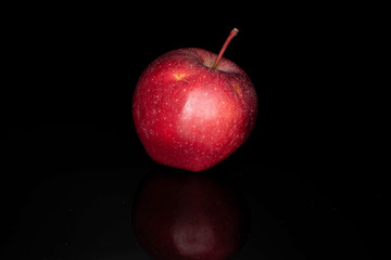 One whole red delicious apple isolated on black glass