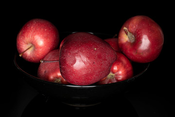 Fototapeta na wymiar Group of five whole red delicious apple in dark bowl isolated on black glass