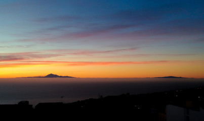 Amanecer desde la isla de La Palma y al fondo en el horizonte Tenerife con su majestuoso volcan del Teide, pico más alto de España y la isla de la Gomera.