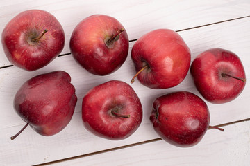 Group of seven whole red delicious apple on white wood