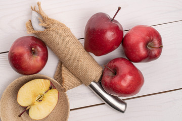 Group of four whole one half of red delicious apple with knife in cloth on white wood