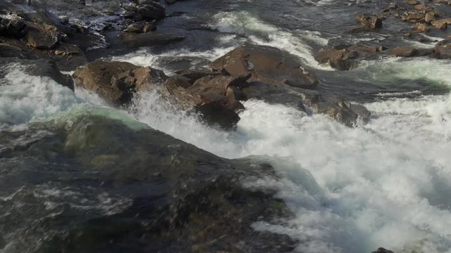 A close-up view of the turbulent waters of the Gaula river, Norway. A mass of water falling from the rocks, whirling and foaming as it travels down the canyon to the valley.