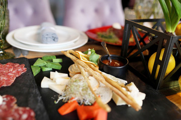 Wedding dinner table service. Wooden dishes with sliced meat and cheese with other snacks stand on a table