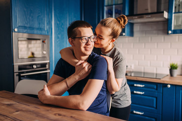Young family husband and wife are at home in the kitchen in an embrace, self-isolation and quarantine