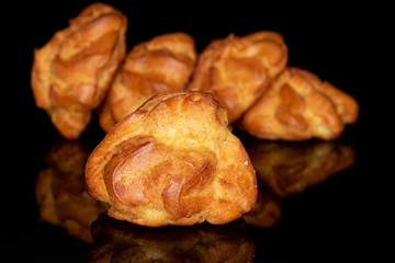 Group of five whole fresh baked profiterole isolated on black glass