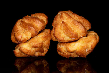 Group of four whole golden fresh baked profiterole isolated on black glass