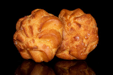 Group of two whole golden fresh baked profiterole isolated on black glass