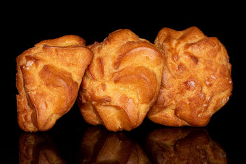 Group of three whole fresh baked profiterole isolated on black glass