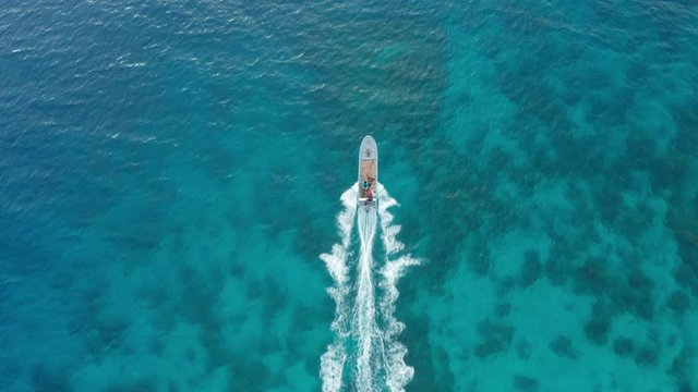 Boat traveling at full speed over the shallow waters in Fiji, top down aerial 4K