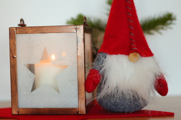 Obraz na płótnie Canvas latern with a candle in it and a gnome with a red hat next to it - home decoration concept