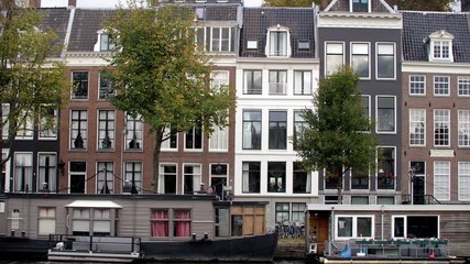 Dutch townhomes with three levels and canal boats along a waterway in Amsterdam Netherlands, dolly right reveal shot