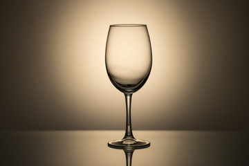 An empty glass goblet on a monochrome background with a spot of light at the back