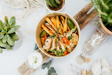 high-protein food with sweet potatoes, chicken breast, peppers and tomatoes in eco box delivered by a delivery service, ordered online, decorated with dried mint and spices on a white background