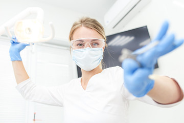 Closeup of dentist tools in hands of womn in blue glowes. Selective focus