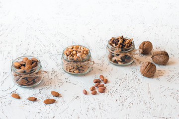 Assorted nuts in glass jars on a white background. Vegan. Healthy eating