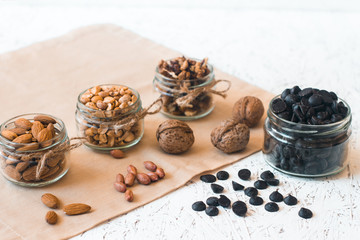 Assorted nuts in glass jars and chocolate on a white background. Vegan. Healthy eating