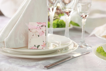 White table setting from above. Elegant empty plate, cutlery, napkin and glass on shabby chic or vintage planked wood table.