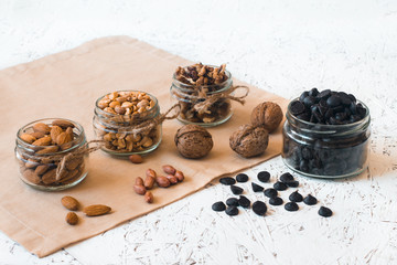 Obraz na płótnie Canvas Assorted nuts in glass jars and chocolate on a white background. Vegan. Healthy eating