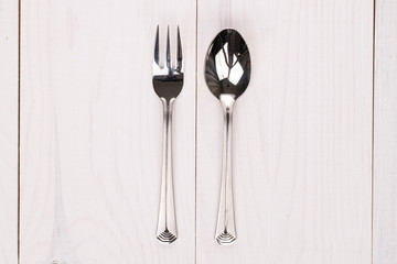 Dessert spoon and fork on white wood