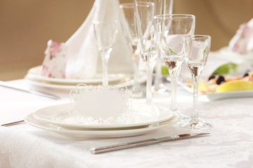 White table setting from above. Elegant empty plate, cutlery, napkin and glass on shabby chic or vintage planked wood table.