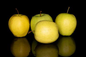 Group of four whole green delicious apple isolated on black glass