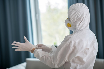 Woman in white workwear wearing protective gloves