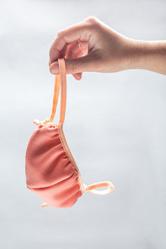 the hand holding a handmade beige fabric face mask on a white background. Vertical orientation