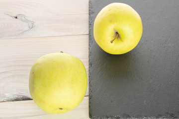 Group of two whole green delicious apple on stone and on white wood