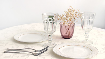 
interior details. table setting. bright plates with devices and glasses on a light table in the room, close-up.