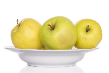 Group of three whole green delicious apple on porcelain plate isolated on white