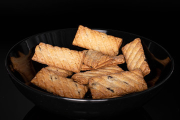 Lot of whole square puff cookie with raisins isolated on black glass