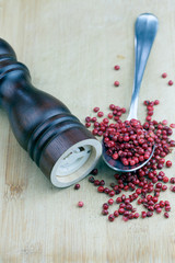 Pink peppercorns, Walnut Pepper Mill and Pink peppercorns in spoon on wooden table
