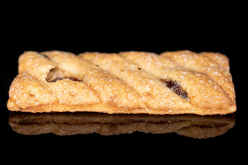 One whole square puff cookie with raisins isolated on black glass