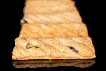 Lot of whole square puff cookie with raisins in row isolated on black glass