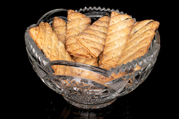 Lot of whole square puff cookie with raisins in crystal bowl isolated on black glass