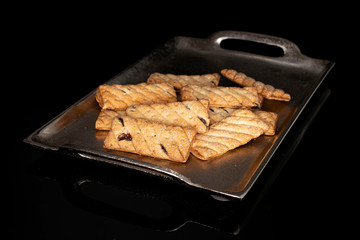 Lot of whole square puff cookie with raisins on tray isolated on black glass
