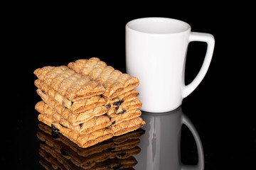 Lot of whole square puff cookie with raisins with coffee isolated on black glass