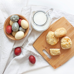 Rustic background. Easter. Colored eggs, milk and homemade bakery products