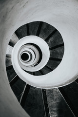 Black and white image of spiral stairs looking down from the top, creating an interesting perspective. 