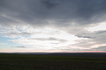 Fototapeta na wymiar Arable land and the pink sunset with clouds.