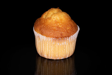 One whole small baked muffin isolated on black glass