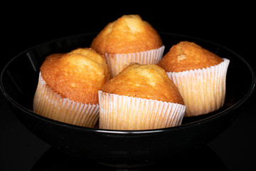 Group of four whole small baked muffin isolated on black glass
